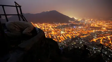 Seorang umat muslim bersujud di puncak Jabal Nur dengan pemandangan Kota Suci Mekah yang diterangi cahaya lampu saat malam hari ketika berziarah dan berdoa menjelang perayaan haji Idul Adha di Mekkah, Arab Saudi (7/9). (Reuters/Ahmed Jadallah)