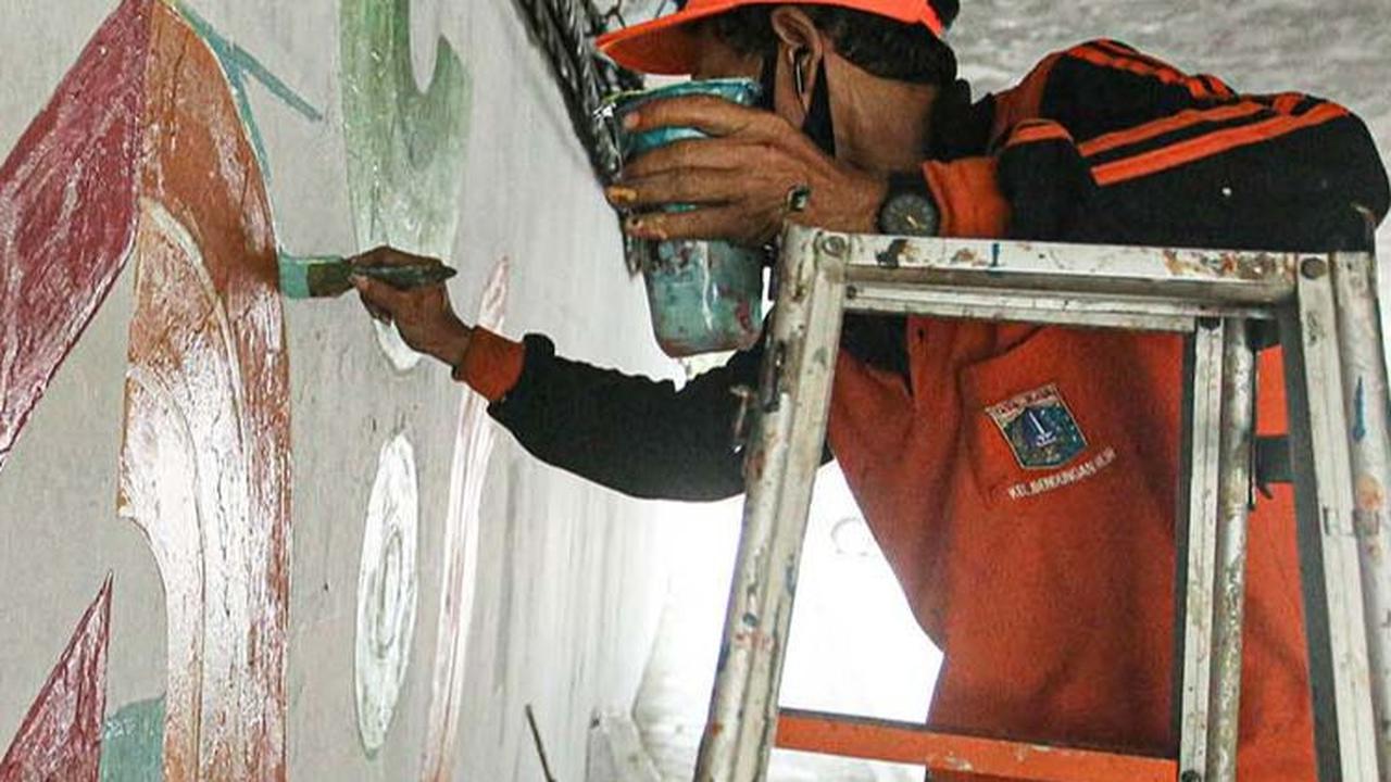 Pasukan oranye sampai menaiki tangga saat menggoreskan kuasnya pada tembok kolong Semanggi.