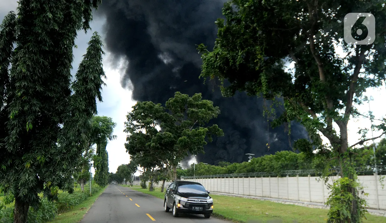 Kendaraan melintas dengan latar belakang kepulan asap akibat kebakaran Kilang Balongan di Indramayu, Jawa Barat, Senin (29/03/2021). Dampak dari terbakarnya kilang minyak Balongan milik PT Pertamina itu mengakibatkan Jalan Raya Balongan-Indramayu ditutup total. (merdeka.com/Arie Basuki)