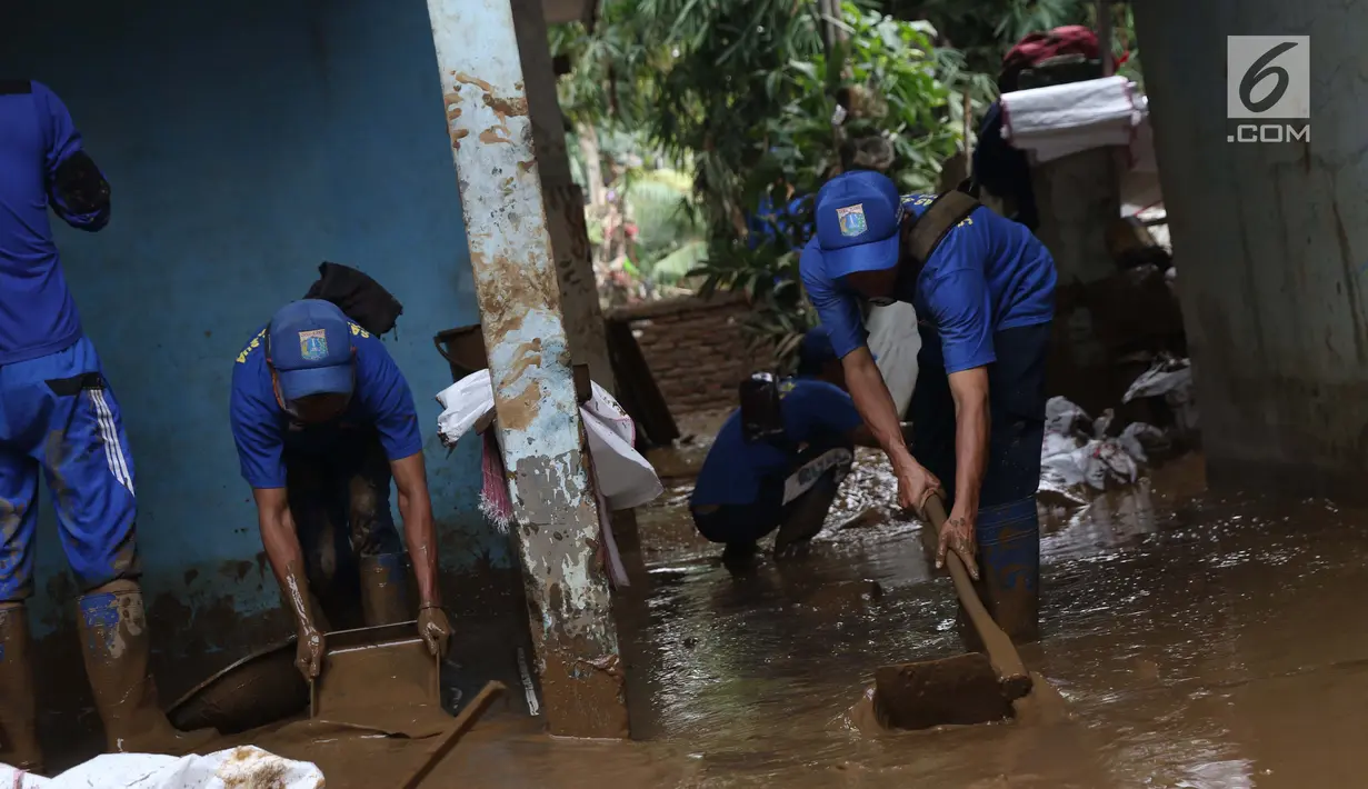 Petugas Sudin LH membersihkan lumpur sisa banjir di salah satu rumah warga di kawasan Rawajati, Jakarta, Sabtu (27/4). Banjir akibat luapan air sungai Ciliwung sempat melanda kawasan ini pada Jumat (26/4). (Liputan6.com/Helmi Fithriansyah)