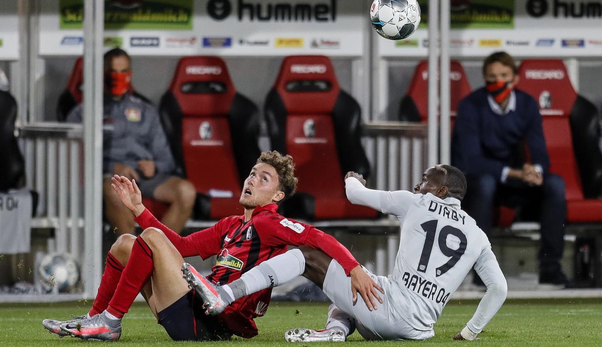 Striker Bayer Leverkusen, Moussa Diaby, berebut bola dengan pemain Freigurg pada laga pekan ke-29 Bundesliga 2019/20 di Schwarzwald-Stadion, Sabtu (30/5/2020) dini hari WIB. Leverkusen menang 1-0 atas Freiburg. (AFP/Ronald Wittek/pool)