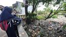 Anak sekolah melihat Kali Pisang Batu yang dipenuhi sampah, Tarumajaya, Bekasi, Jawa Barat, Rabu (9/1). Warga tetap beraktivitas sehari-hari meski bau tak sedap menghantui mereka akibat tumpukan sampah di Kali Pisang Batu. (Merdeka.com/Iqbal S. Nugroho)