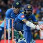 Pemain kriket Sri Lanka Niroshan Dickwella (kana) diawasi oleh wicketkeeper India Mahendra Singh Dhoni burusaha memukul bola dalam pertandingan kriket One Day International (ODI) di Dambulla (20/8). (AFP Photo/Lakruwan Wanniarachchi)