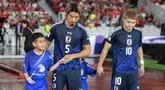 Pemain Jepang, Hidemasa Morita (kedua kiri) menuntun anak kecil yang ditugaskan sebagai player escort dalam pertandingan lanjutan putaran ketiga Grup C Kualifikasi Piala Dunia 2026 melawan Timnas Indonesia di Stadion Utama Gelora Bung Karno (SUGBK), Senayan, Jakarta, Jumat (15/11/2024). (Bola.com/Bagaskara Lazuardi)
