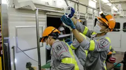 Petugas membersihkan handgrip bagian dalam pada rangkaian KRL Jabodetabek di Dipo Depok, Jawa Barat, Jumat (13/3/2020). Pembersihan bagian luar dan bagian dalam kereta menggunakan cairan disinfektan guna mengantisipasi penyebaran virus corona (Covid-19). (Liputan6.com/Faizal Fanani)
