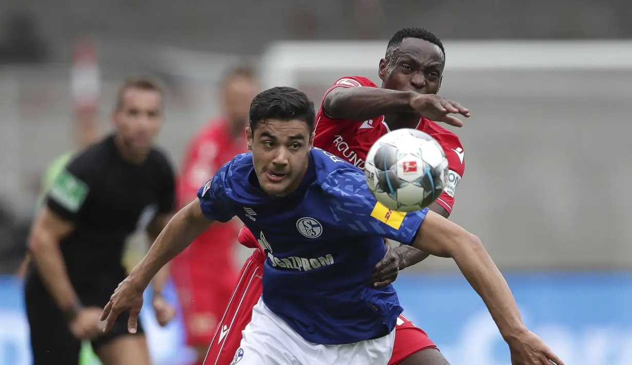 Pemain Union Berlin, Anthony Ujah, berebut bola dengan pemain Schalke, Ozan Kabak, pada laga Bundesliga di Weserstadion Minggu (7/6/2020). Kedua tim bermain imbang 1-1. (AP/Michael Sohn)