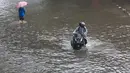 Ketinggian air yang menggenangi permukiman dan jalan bervariasi, mulai dari sekitar 20 sentimeter hingga mencapai hampir satu meter di titik-titik tertentu. Tampak dalam foto, pengendara dan pejalan kaki melintasi banjir yang menggenangi Jalan Jembatan Tiga Raya, Jakarta Utara, Senin (12/1/2026). (merdeka.com/Arie Basuki)