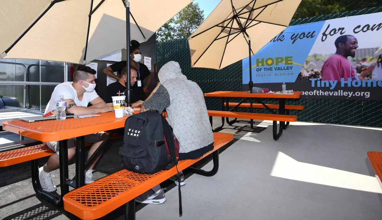 Anggota staf (kiri) mengumpulkan informasi dari pendatang baru di Tarzana Tiny Home Village di lingkungan Tarzana, Los Angeles, California, Amerika Serikat, 9 Juli 2021. Selain Hollywood, California juga menampung tenda-tenda puluhan ribu tunawisma di seluruh kota. (Robyn Beck/AFP)