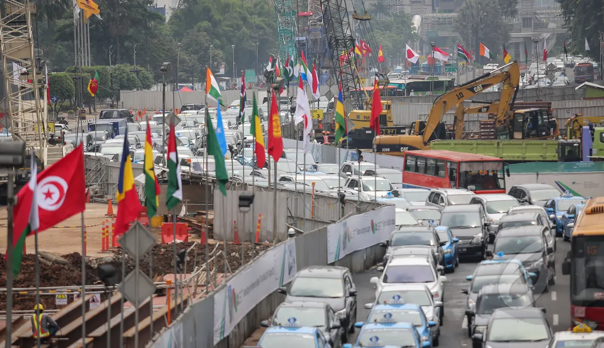 Deretan bendera negara peserta Konferensi Asia Afrika ke-60 terpasang di dinding proyek MRT kawasan Bundaran HI, Jakarta, Selasa (14/4/2015). Persiapan ini dilakukan di sepanjang jalur yang dilalui peserta negara KAA ke-60.  (Liputan6.com/Faizal Fanani)