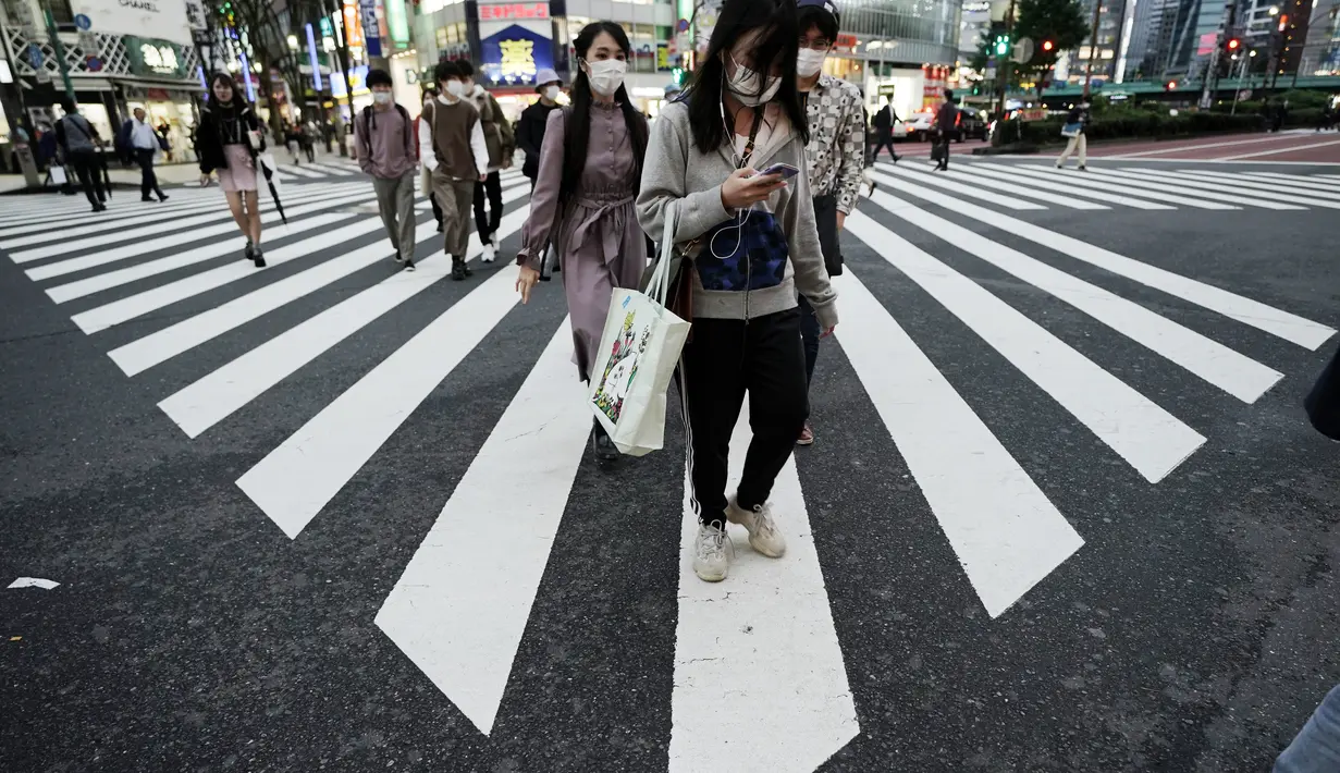 Orang-orang yang mengenakan masker pelindung untuk membantu mengekang penyebaran virus corona berjalan di tempat penyeberangan pejalan kaki di Tokyo (15/10/2020). Ibukota Jepang mengonfirmasi lebih dari 280 kasus virus korona baru pada hari Kamis. (AP Photo/Eugene Hoshiko)