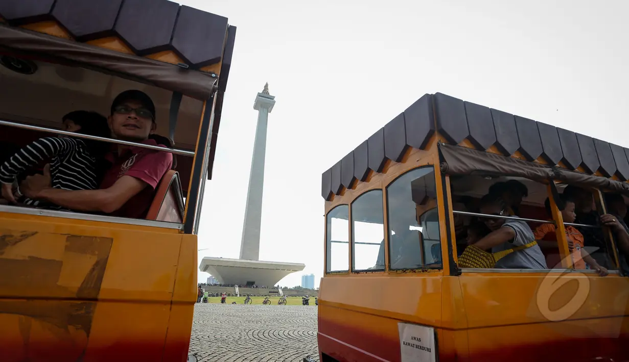 Para pengunjung Monas tampak menikmati pemandangan sekitar kawasan Monas dengan menaiki mobil gandeng, Jakarta, Kamis (14/5/2015). (Liputan6.com/Faizal Fanani)