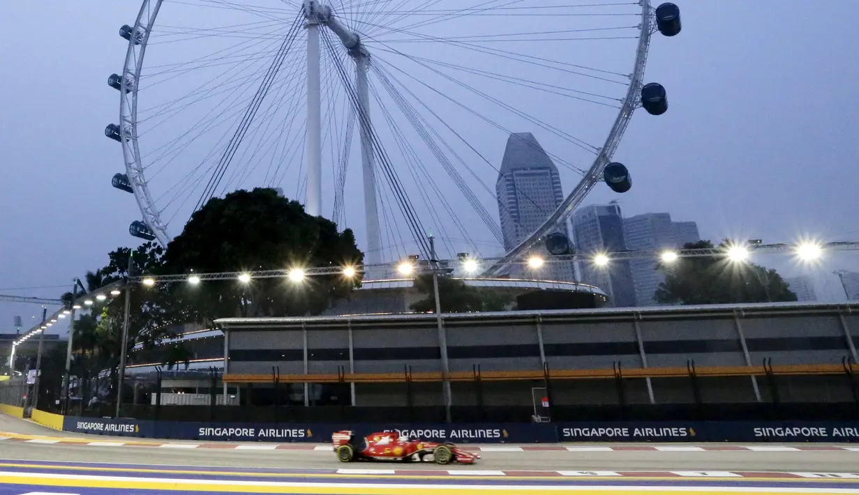 Pembalap Ferrari Formula 1, Sebastian Vettel saat melakukan sesi latihan jelang Grand Prix Singapura F1 di Sirkuit Marina Bay (18/9/2015). Kabut asap yang menyelimuti sirkuit tak menyurutkan pembalap untuk tetap melakukan pemanasan. (REUTERS/Tim Chong)