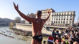 Simone Carabella dari Italia dengan slogan 'No Green Pass' terlukis pada punggungnya menyapa orang-orang saat dia bersiap untuk melompat ke Sungai Tiber dari Jembatan Cavour setinggi 18 meter (59 kaki) untuk merayakan Tahun Baru di Roma, 1 Januari 2022. (AP Photo/Riccardo De Luca)
