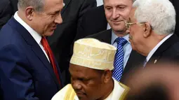 PM Israel Benjamin Netanyahu (kiri) berjabat tangan dengan Presiden Palestina Mahmud Abbas di depan Presiden Selandia Baru disela foto bersama pada KTT Perubahan Iklim, Conference of Parties (COP) 21 di Prancis, Senin (30/11). (AFP/POOL/MARTIN BUREAU)