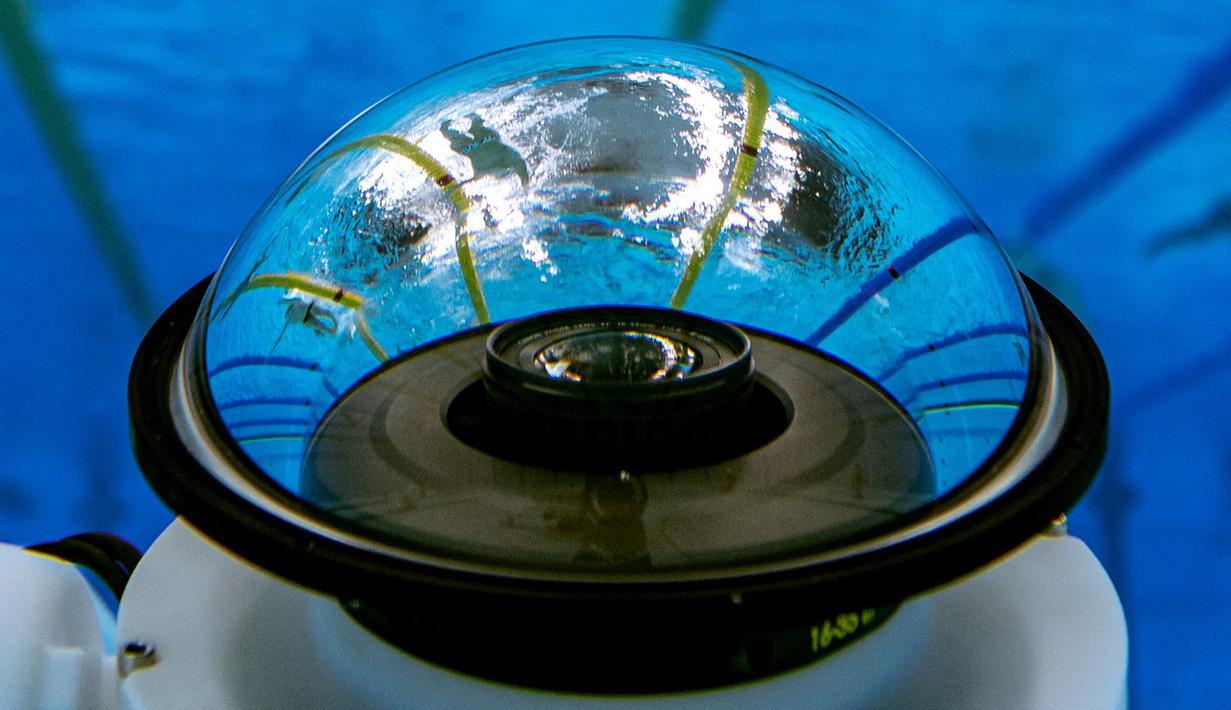 Pemandangan bawah air menunjukkan atlet yang tercermin dalam lensa kamera robot bawah air saat mereka melakukan pemanasan menjelang acara renang selama Olimpiade Tokyo 2020 di Tokyo Aquatics Center, Tokyo pada 26 Juli 2021.
(AFP/François-Xavier Marit)