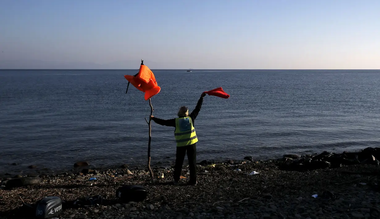 Seorang relawan memberikan tanda kepada Puluhan imigran dan Pengungsi dari Suriah di pulau Lesbos, Yunani, Senin (9/11). Sejak tahun 2015 lebih dari 590.000 imigran menyeberang ke Yunani akibat perang yang terjadi di Suriah. (REUTERS/Alkis Konstantinidis)