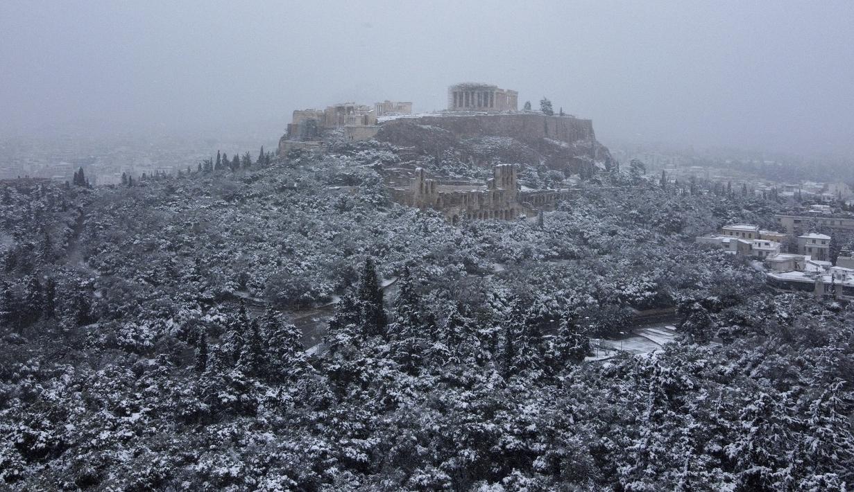 Bukit Acropolis kuno tertutup salju di Athena, Yunani, Senin (24/1/2022). Hujan salju lebat telah mengganggu lalu lintas udara di Athena dan kota tetangga terbesar di Turki, Istanbul, sementara beberapa pulau Aegea dan sebagian besar wilayah Turki diselimuti oleh salju.  (AP Photo/Michael Varaklas)