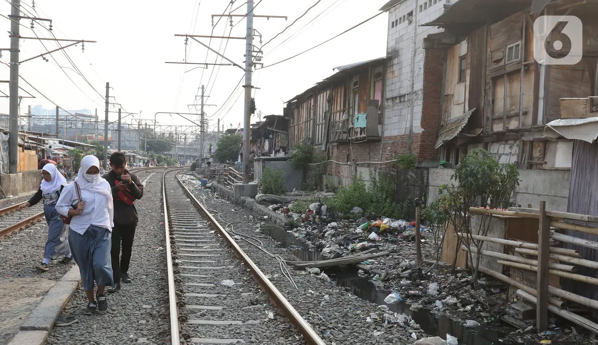 Sejumlah pelajar berjalan menyusuri perlintasan kereta di Kampung Muka, Ancol, Jakarta, Selasa (5/11/2019). Pemprov DKI Jakarta mengusulkan anggaran konsultan penataan kampung kumuh sebesar Rp 556 juta per rukun warga (RW) pada rancangan APBD 2020. (Liputan6.com/Herman Zakharia)
