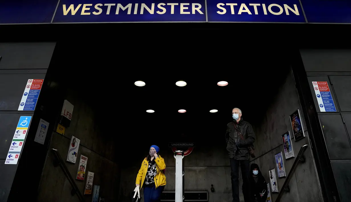 Pelancong mengenakan masker saat mereka meninggalkan stasiun kereta bawah tanah di Westminster, London, Kamis (9/12/2021). Perdana Menteri Inggris Boris Johnson telah mengumumkan pembatasan yang lebih ketat untuk membendung penyebaran varian baru Covid-19, omicron. (AP Photo/Frank Augstein)