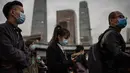 Orang-orang yang memakai masker untuk mengurangi risiko tertular virus corona COVID-19 sedang menunggu di lampu merah untuk menyeberang jalan selama jam sibuk di Beijing, China pada 14 Oktober 2020. (Photo by NICOLAS ASFOURI / AFP)
