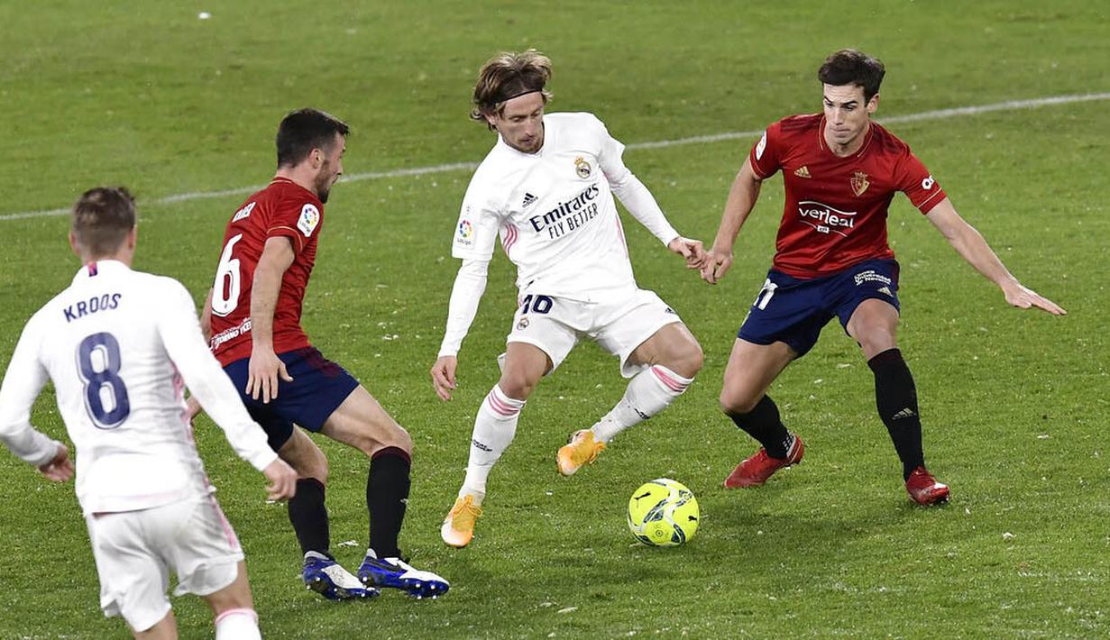 Gelandang Real Madrid, Luka Modric, berusaha melewati pemain Osasuna pada laga Liga Spanyol di Stadion El Sadar, Sabtu (9/1/2021). Kedua tim bermain imbang 0-0. (AP/Alvaro Barrientos)