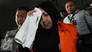 Komisaris CV Timur Alam Raya, Sri Astuti menutupi wajah usai menjalani pemeriksaan di KPK, Jakarta, Senin (22/8). Sri Astuti diduga melakukan penyuapan terkait pengadaan pupuk urea di PT Berdikari tahun anggaran 2010-2012. (Liputan6.com/Helmi Afandi)