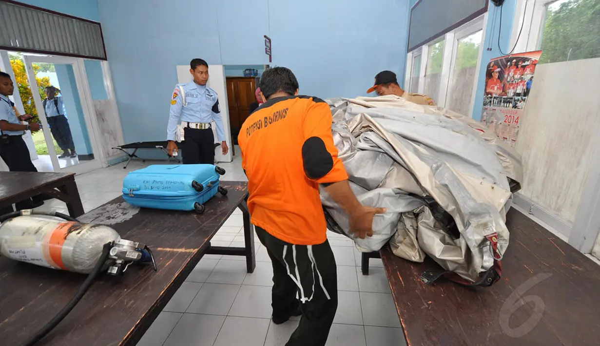 Beberapa petugas merapikan sejumlah barang temuan yang diduga berasal dari pesawat AirAsia QZ 8501 di salah satu ruangan di Lanud Iskandar, Pangkalan Bun, Kalimantan Tengah, Selasa (30/12/2014). (Liputan6.com/Miftahul Hayat)