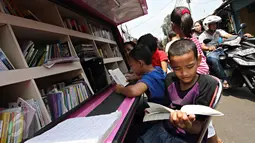 Anak-anak membaca buku yang disediakan perpustakaan keliling di kawasan Tanah Abang, Jakarta, Minggu (11/10). Keberadaan perpustakaan keliling untuk meningkatkan minat baca pada anak-anak. (Liputan6.com/Immanuel Antonius)