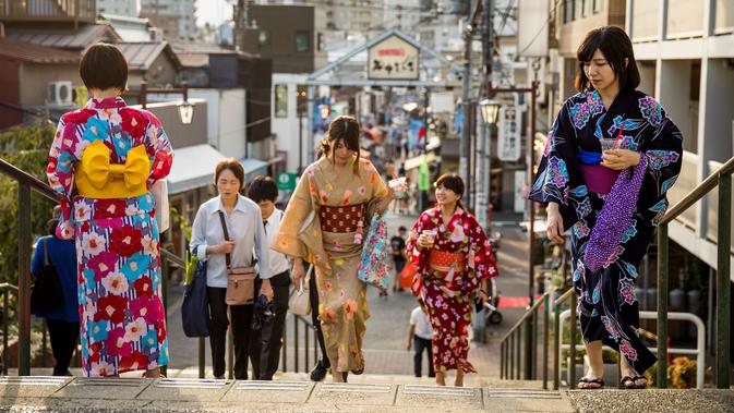 Sejumlah wanita memakai pakaian tradisional berjalan di sepanjang jalan perbelanjaan Yanaka Ginza di pusat Tokyo (30/9/2019). Wilayah Yanaka di ibukota Jepang dikenal sebagai salah satu yang paling kuno dan unik. (AFP Photo/Odd Andersen)