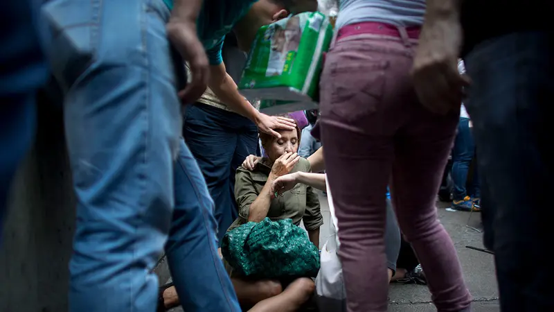 Perempuan pingsan saat antre makanan. Hidup kian tak menentu di Venezuela di tengah krisis ekonomi yang terjadi (AP PHOTO / ARIANA CUBILLOS)