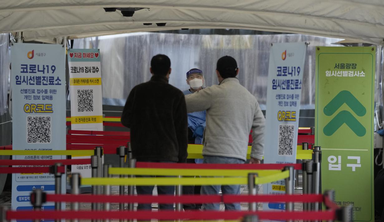 Pekerja medis berbicara kepada orang-orang bahwa tes virus corona pagi hari telah selesai di tempat pengujian darurat di Seoul, Jumat (10/12/2021). Korea Selatan melaporkan lebih dari 7.000 kasus COVID-19 baru untuk ketiga hari berturut-turut pada hari Jumat ini. (AP Photo/Ahn Young-joon)