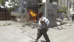 Seorang pria melintasi mesin ATM bitcoin bernama Chivo yang dibakar dalam protes terhadap Presiden Nayib Bukele di San Salvador, El Salvador, Rabu (15/9/2021). Ribuan warga Salvador berdemonstrasi menentang bitcoin, yang disahkan sebagai alat pembayaran oleh pemerintah. (AP Photo/Ivan Manzano)