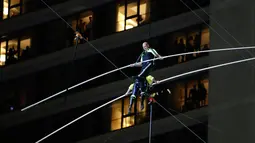 Aerialists Nik Wallenda (atas) melangkahi saudara perempuannya Lijana Wallenda saat melintasi seutas kawat di ketinggian 396 meter, Times Square, New York, AS, Minggu (23/6/2019). Nik dan Lijana berjalan dari sisi berbeda yang digantung di antara dua menara Times Square. (AP Photo/Jason Szenes)