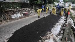 Petugas Sudin Bina Marga Jakarta Pusat memperbaiki jalan ambles di Jalan Inspeksi Kali Ciliwung, Kenari, Rabu (19/1/2022). Jalan yang berada di belakang RSCM tersebut ambles sepanjang 40 meter akibat terkikis oleh hujan deras kemarin sehingga menyulitkan akses warga. (merdeka.com/Iqbal S Nugroho)
