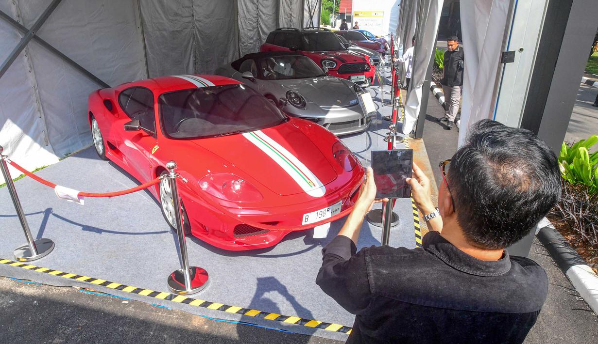 Pengunjung memfoto mobil mewah yang siap dilelang terbuka pada acara Badan Pemulihan Aset (BPA) Kejaksaan Agung Fair 2026 di Jakarta, Kamis (21/5/2026). (merdeka.com/Arie Basuki)