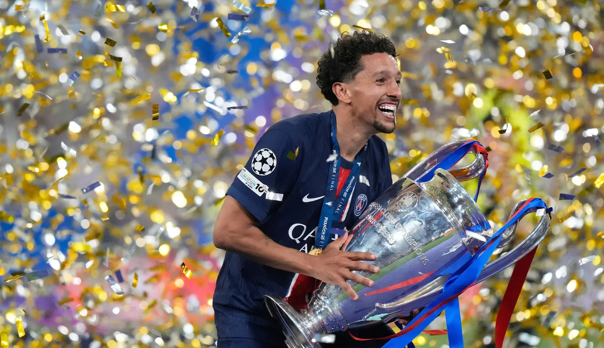 Kapten Paris Saint-Germain (PSG), Marquinhos, mengangkat trofi usai menjuarai Liga champions 2024/2025 di Stadion Allianz Arena, Minggu (01/06/2025) dini hari WIB. (AP Photo/Luca Bruno)