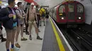 Orang-orang menunggu tube di peron saat mengikuti acara tahunan "No Trousers Tube Ride" di London, Minggu (8/1/2023). No Trousers Tube Ride kembali ke London, pertama kalinya acara tersebut berlangsung sejak Januari 2020. (AP Photo/Kin Cheung)