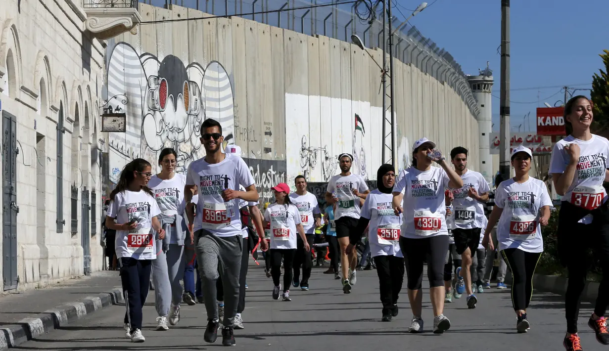 Sejumlah peserta berlari menyusuri tembok pemisah Israel selama Right to Movement Maraton di kota Bethlehem, Palestina, Jumat (1/4). Tembok sejauh 700 km ini dijadikan obyek berlari para peserta. (REUTERS / Ammar Awad)