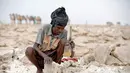 Seorang pria mengolah tanah untuk manjadi garam di tambang garam di Danakil Depression, Afar, Ethiopia (28/3). Para pekerja hanya menggunakan alat pencungkil dan kapak sederhana untuk memotong bongkahan garam. (AFP Photo/Zacharias Abubeker)