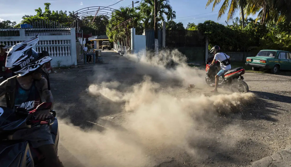 Seorang pengendara motor menendang debu pada pertemuan sore oleh pengendara skuter listrik untuk memamerkan aksi dan balapan di Havana, Kuba, pada 15 Juli 2022. Kuba telah dibanjiri dalam beberapa tahun terakhir dengan "motorinas", begitu skuter listrik ini disebut di pulau itu, sebuah mode bagi banyak orang, tetapi juga solusi untuk masalah transportasi dan kekurangan bahan bakar yang melanda negara Karibia itu. (AP Photo/Ramon Espinosa)