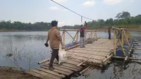 Warga sedang berjalan menuju rakit bambu untuk menyebrangi perairan Saguling di wilayah Kampung Sekecengek, Desa Cangkorah, Kecamatan Batujajar, Kabupaten Bandung Barat (KBB)/Liputan6.com