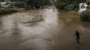 Seorang anak melompat ke Sungai Ciliwung saat banjir melanda Jalan Bina Warga Rt 005/Rw 07 Kelurahan Rawa Jati, Jakarta, Senin (8/2/2021). Banjir setinggi 60-190 cm tersebut disebabkan oleh luapan air Sungai Ciliwung dan curah hujan Jakarta yang tinggi. (Liputan6.com/Johan Tallo)