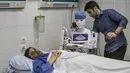 Mahmoud El Komy, seorang insinyur mekatronika, menguji prototipe robot CIRA-03 kendali jarak jauh yang didanai sendiri untuk membantu dokter dalam menjalankan tes pada pasien yang dicurigai COVID-19 di rumah sakit swasta di kota Tanta, Mesir pada 20 Maret 2021. (Khaled DESOUKI/AFP)
