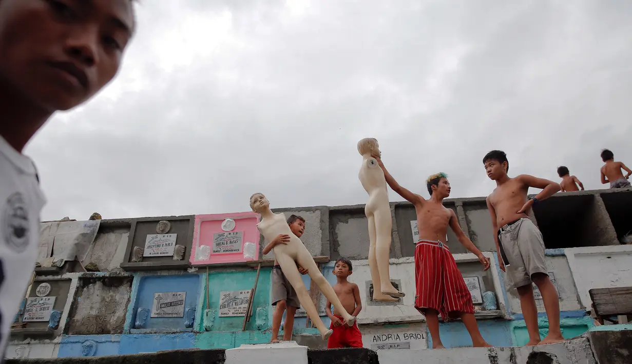 Anak-anak bermain manekin d iatas kuburan di North Cemetery, Manila, Filipina, Minggu (16/10). Pemakaman ini dihuni sekitar 6.000 warga, beberapa dari mereka mewarisi tempat ini dari orang tua. (Reuters/ Damir Sagolj)