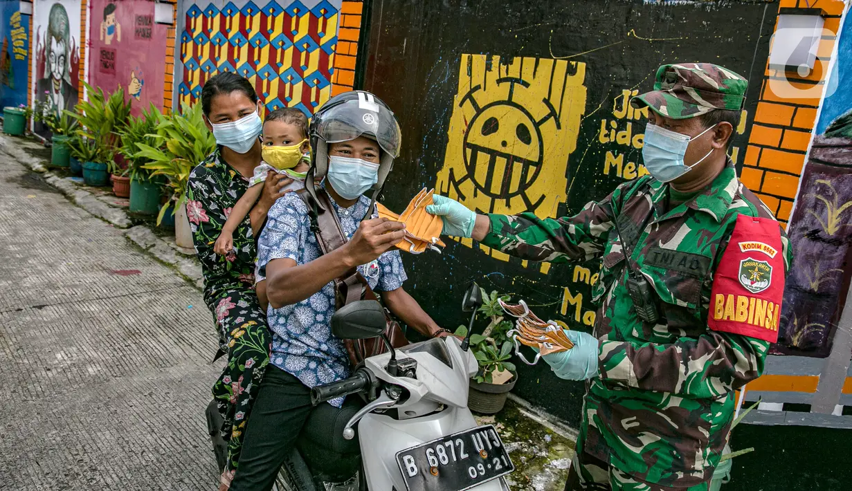 Anggotan TNI membagika masker kepada pengendara sepeda motor di Sunter Muara, Tanjung Priok, Jakarta, Selasa (9/2/2021). Tujuan kegiatan tersebut agar masyarakat menyadari peran penting penggunaan masker dalam memutus mata rantai penyebaran COVID-19. (Liputan6.com/Faizal Fanani)
