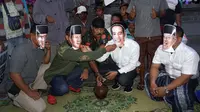 Jokowi dan Prabowo yang diperankan warga dengan mengenakan topeng wajah kedua tokoh itu terlihat sedang saling menyuapi saat berbuka puasa.(Liputan6.com/Fajar Abrori)