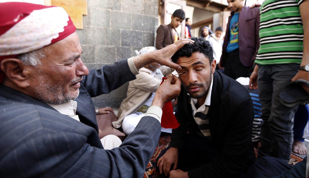 Seorang pria saat kelopak matanya dirias dengan kohl atau celak di  Masjid Agun di kota tua ibukota Sanaa, Yama, (19/5). Pemakaian kohl atau celak diyakini muslim Yaman mampu membersihkan dan melindungi mata dari penyakit. (AFP Photo/Mohammed Huvais)