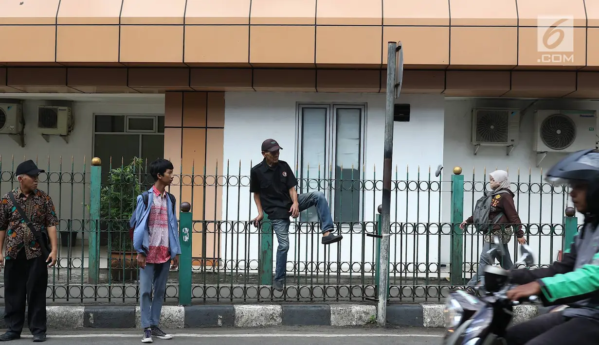 Penumpang menaiki pagar pembatas untuk keluar dari Stasiun Cikini di Jakarta, Jumat (22/3). Jauhnya akses pintu masuk dan keluar stasiun menyebabkan sebagian orang mempersingkat waktu dengan melompat pagar pembatas. (Liputan6.com/Immanuel Antonius)