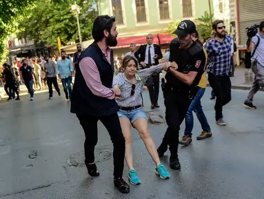 Petugas polisi anti huru hara berusaha menghalangi peserta pawai masuk ke lokasi parade Gay Pride di Istiklal Street Turki, pusat kota Istanbul, bertepatan dengan hari raya Idul Fitri 1438 Hijriah, Minggu (25/6). (YASIN AKGUL/AFP)