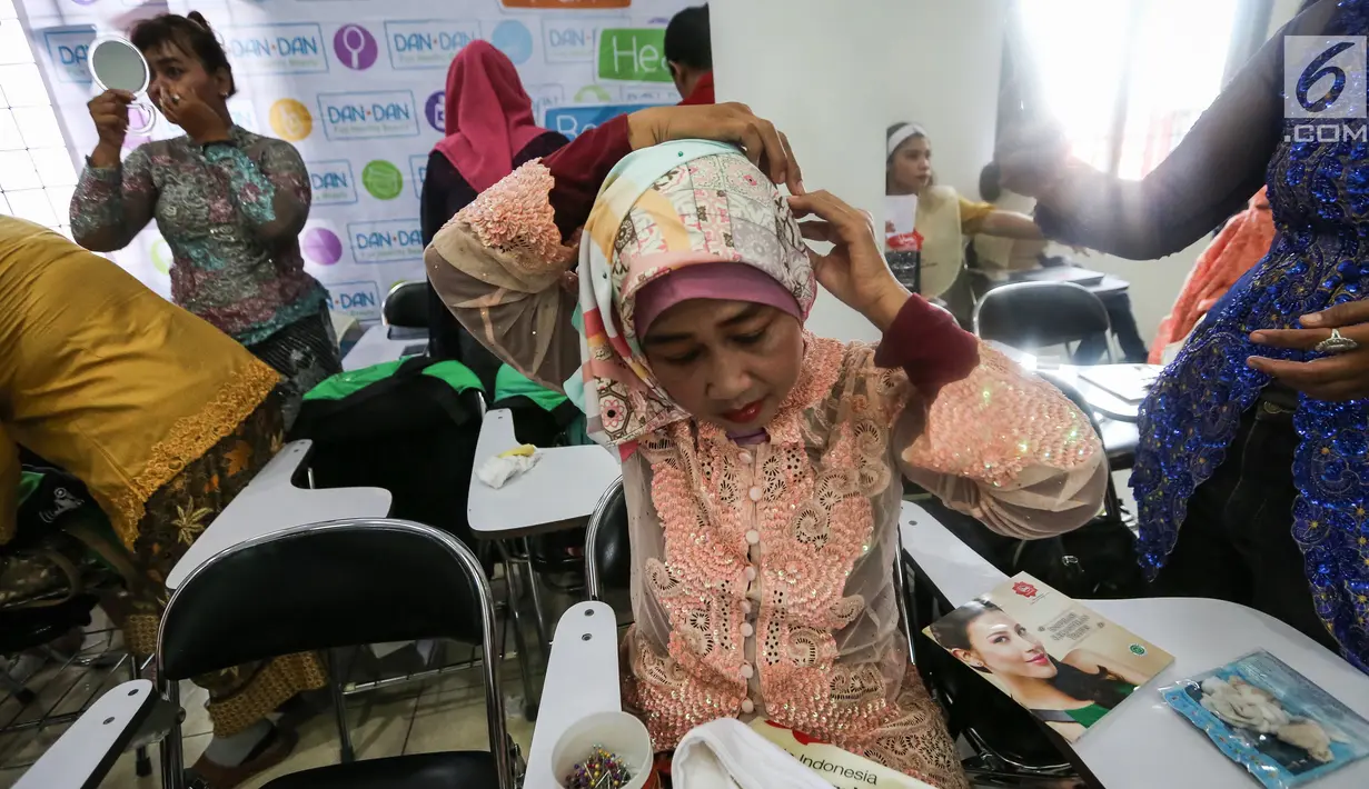 Seorang pengemudi ojek online wanita memasang jilbab jelang peragaan busana di Rawamangun, Jakarta, Jumat (20/4). Kegiatan tahunan ini sebagai bentuk apresiasi GO-Mart DanDan kepada mitra driver. (Liputan6.com/Fery Pradolo)